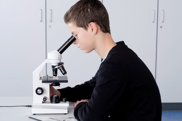Science Kits - Schülerversuche für die Sek 1. Ein Schüler experimiert mit einem Mikroskop in der Biologie.