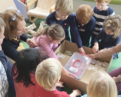 Die Kinder der Kita St. Raphael packen neugierig einen Karton mit verschiedenen Gegenständen aus.